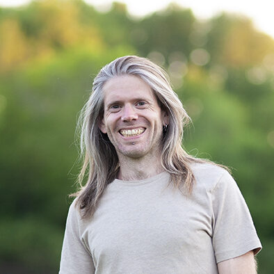 Portrait of Stefaan, a holistic therapist, standing in a serene meadow.